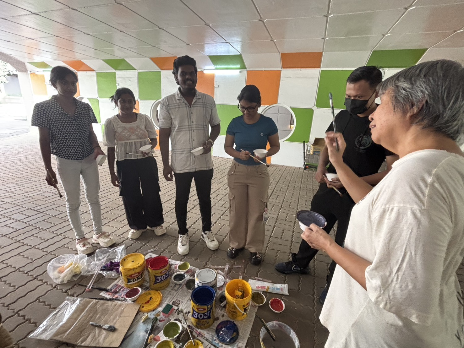 學生們聆聽藝術家的繪畫指引。Students paid close attention to the artists’ guidance during the mural creation.